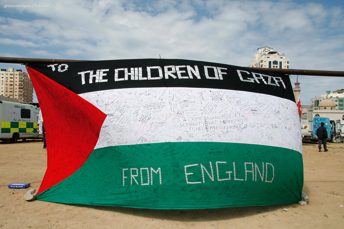 School children sign messages on the Palestinian flag in solidarity with the people in Gaza